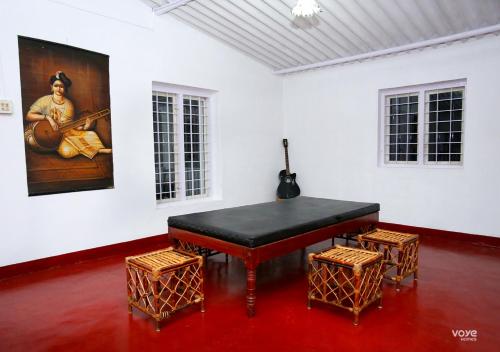 un piano noir dans une pièce blanche avec deux tabourets dans l'établissement Moonlight Munnar Forest Bungalow with Private Waterfalls by VOYE HOMES, à Kanthalloor