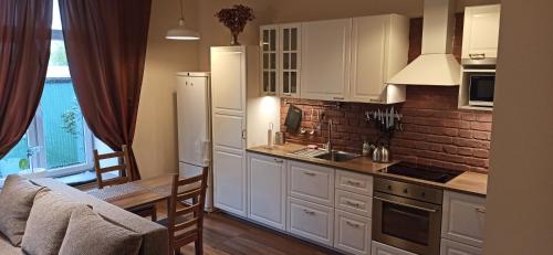 a kitchen with white cabinets and a brick wall at Studio flat in a historical XIX c. building. in Kaunas