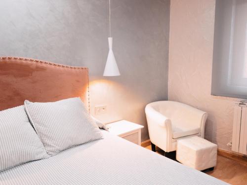 a bedroom with a bed and a white chair at Hotel Los Toreros in Tordesillas
