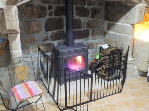 a stone fireplace in a room with a chair at L'Oustal dè Pèiro in Le Bourg
