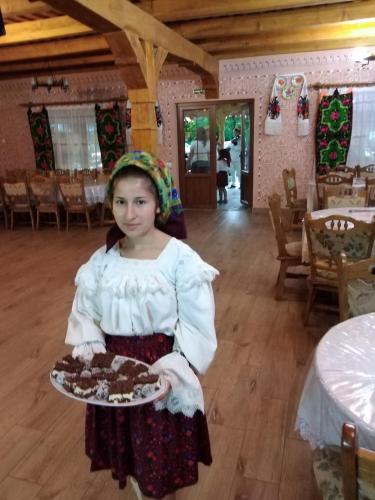 a young girl holding a plate of chocolate cake at Pensiunea Valea Branzei in Năneşti