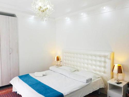 a white bedroom with a bed and two lamps at Apartment 31 August in Chişinău