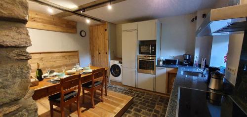 a kitchen with a table and a kitchen with a stove at O Près de la Lienne, maison de campagne de charme, accord parfait entre confort et authenticité in Lierneux