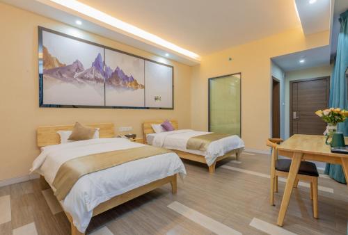 two beds in a hotel room with a table and a table at Yangshuo Yi Landscape Hotel in Yangshuo