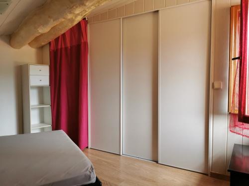 a bedroom with white cabinets and a red curtain at Appartement duplex in Le Boulou
