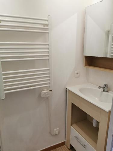 a white bathroom with a sink and a mirror at Appartement duplex in Le Boulou