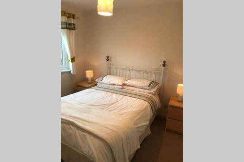 um quarto com uma cama com lençóis brancos e almofadas em Kingseat 3 Bed Home With Fast Fibre WiFi &Parking em Newmacher
