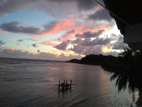 a sunset over the ocean with a dock in the water at Calibishie Sandbar in Calibishie