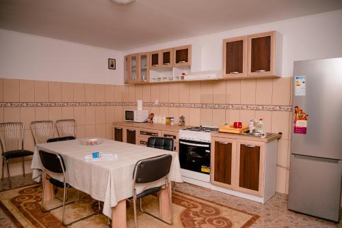 a kitchen with a table and a refrigerator at Pensiunea Happy Flowers in Greci