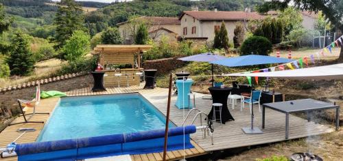 een terras met een zwembad en een tafel en een parasol bij Halte du Vert Coteau in Chevinay