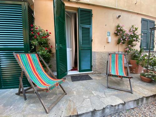 two chairs sitting outside of a house with green doors at Soffio Di Mare in Camogli