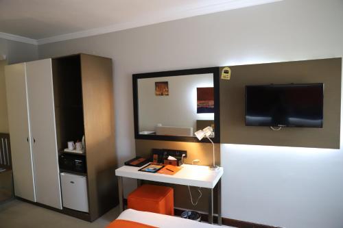 a room with a bed and a desk with a television at Citymax Hotel Aswan in Aswan
