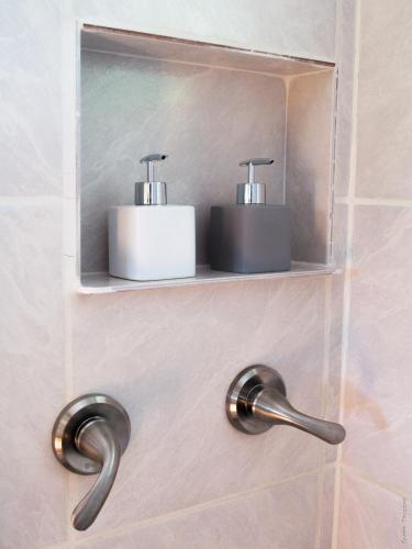 a bathroom with two soap dispensers on a wall at Horse Cottage in Sarteneja