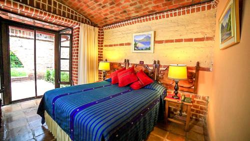 - une chambre avec un lit doté d'oreillers bleus et rouges dans l'établissement Hotel San Buenaventura de Atitlán, à Panajachel