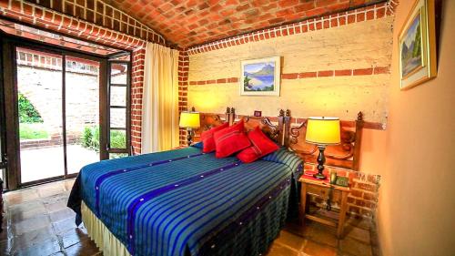 a bedroom with a bed with blue and red pillows at Hotel San Buenaventura de Atitlán in Panajachel