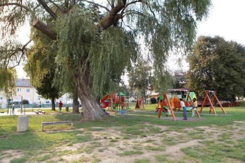 a park with a large tree and a playground at Mrežnički kutak in Duga Resa