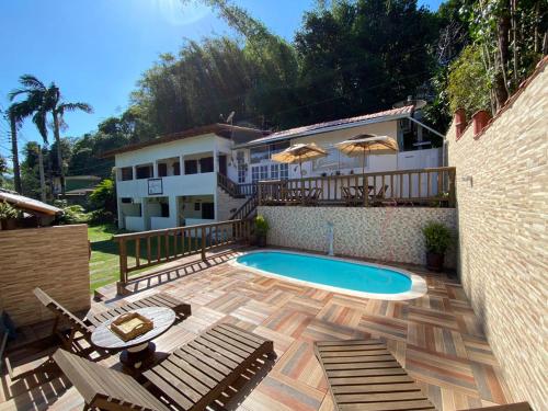 a backyard with a swimming pool and a house at Toca dos Pássaros in Boicucanga