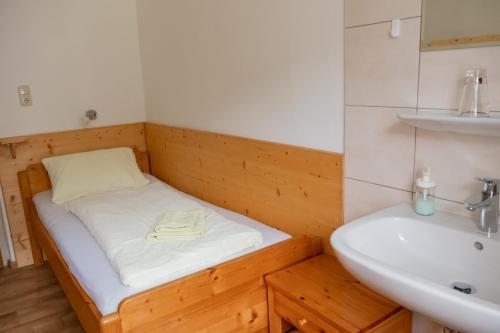 a small room with a bed and a sink at Haus Alpenrose in Obertraun