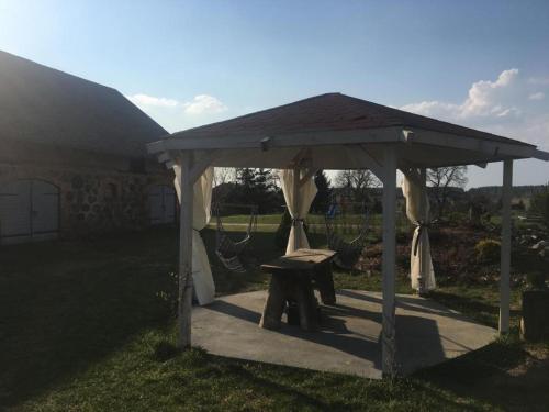 a gazebo with a picnic table and a bench at Placówka - całoroczny dom wakacyjny in Wydminy