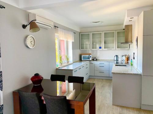 a kitchen with white cabinets and a table with chairs at Słupsk forest PREMIUM LOVE APARTAMENT M5 - Kaszubska street 18 - Wifi Netflix Smart TV50 - double bathtub - up to 4 people full - pleasure quality stay in Słupsk