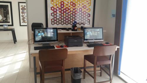 a desk with three computer monitors and two chairs at Holiday Inn Express Slidell by IHG in Slidell