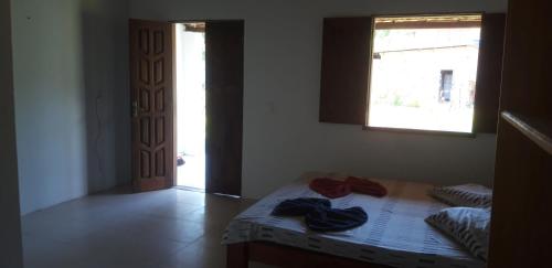 a bedroom with a bed and a window and a door at Sem Fronteiras in Ilha de Boipeba