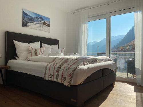 a bedroom with a large bed with a large window at VitAllgäu-Neues Studio mit Königscard in Pfronten