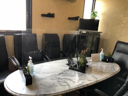 a marble table with plants on it in a room with chairs at Hotel Satellite in Satsumasendai