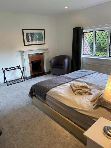 a bedroom with a bed and a chair and a fireplace at Chichester Retreat with Large Private Mature Garden in Chichester