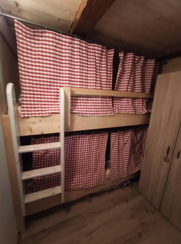 a bunk bed in a room with red and white sheets at Almhütte Andrea in Wildschönau