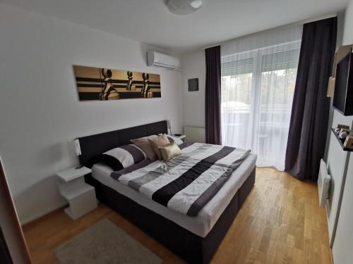 a bedroom with a bed and a large window at Freedom Apartman in Hajdúszoboszló