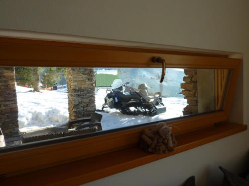 a window with a motorcycle parked in the snow at Luxury Wellness Apartment in Rokytnice nad Jizerou