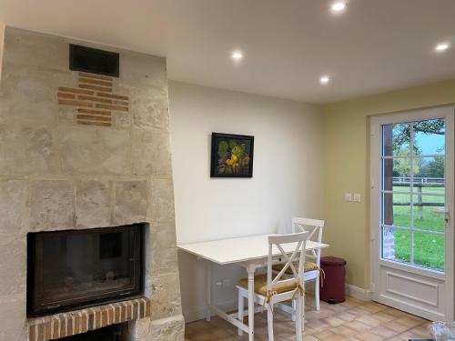 un salon avec une cheminée, une table et une télévision dans l'établissement La Longere du Haras, à Manerbe