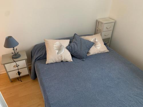 a bedroom with a bed with blue sheets and pillows at Appartement Cabourg bord de mer in Cabourg