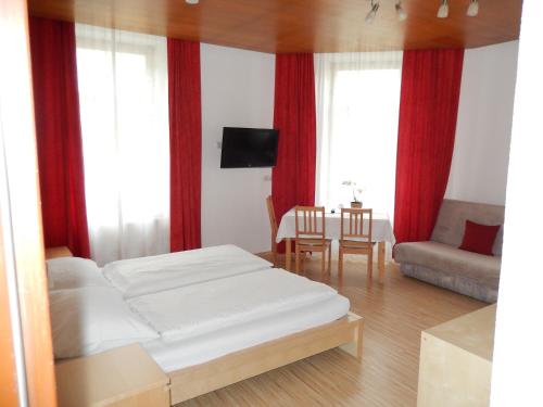 Hotel "Wilder Mann" في لينز: غرفة نوم مع سرير وغرفة معيشة مع ستائر حمراء