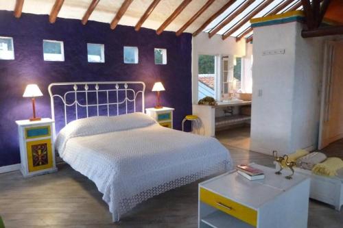 een slaapkamer met een wit bed en een paarse muur bij ARCOS DE LA LOMA in Paipa