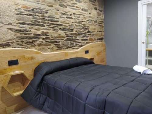 Cama en habitación con pared de piedra en Apartamentos turísticos o palomar, en Vilalba