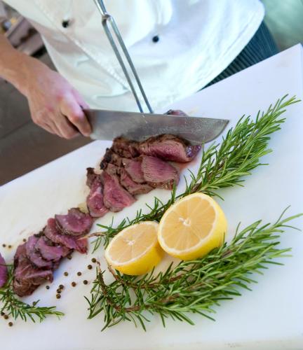 a person cutting a piece of meat with a knife at Hotel Atlantic Riviera Mare in Misano Adriatico