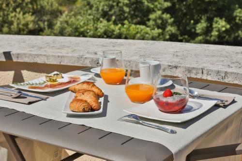 a table with breakfast foods and glasses of orange juice at Quintessence Provence in Goult