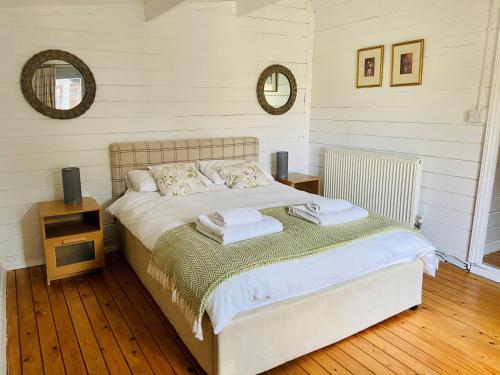 a bedroom with a bed and two mirrors on the wall at Spacious Garden Lodge at The Chestnuts, Norfolk in Norwich