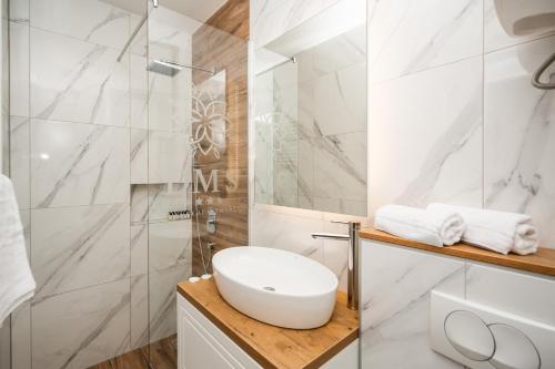 a white bathroom with a sink and a shower at DMS Apartments & Suites Sarajevo in Vogošća