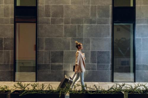 a woman walking down a sidewalk with a suitcase at LUST PREMIUM Apartments in Kragujevac