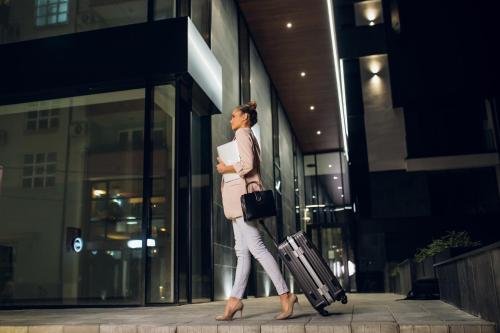 una mujer caminando por un edificio con su equipaje en LUST Premium Apartments en Kragujevac
