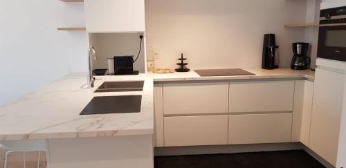 uma cozinha com armários brancos e uma bancada em Nieuwbouwappartement Lippenslaan met 2 slaapkamers - WIFI - 6 personen em Knokke-Heist