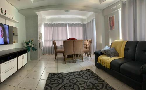 a living room with a couch and a dining room at Excelente apt para veraneio c Wi-Fi tv e box in Capão da Canoa