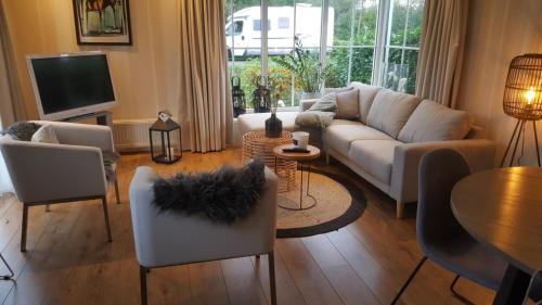 un soggiorno con divano, sedie e tavolo di Resort Venetie Chalet nr.42 a Giethoorn