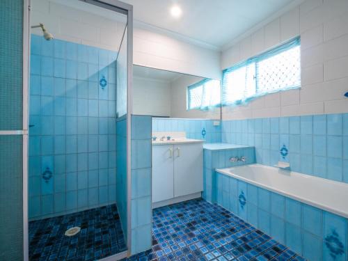 uma casa de banho em azulejos azuis com uma banheira e um chuveiro em Croydon Ave 50 Currimundi em Kawana Waters
