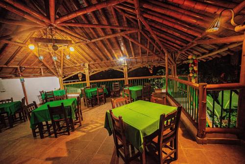 a restaurant with green tables and chairs on a deck at Eco Hotel las Palmas in Armenia