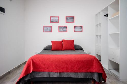 Un dormitorio con una cama con una manta roja. en Aurelia, en Valeria del Mar