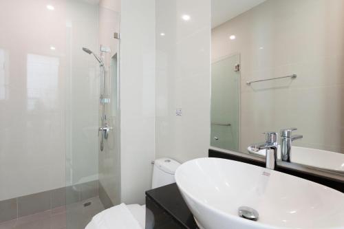 Un baño blanco con lavabo y ducha. en Cozy, Great location at heart of Nimman Rd., en Chiang Mai